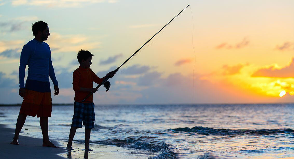 father and son fishing on beach